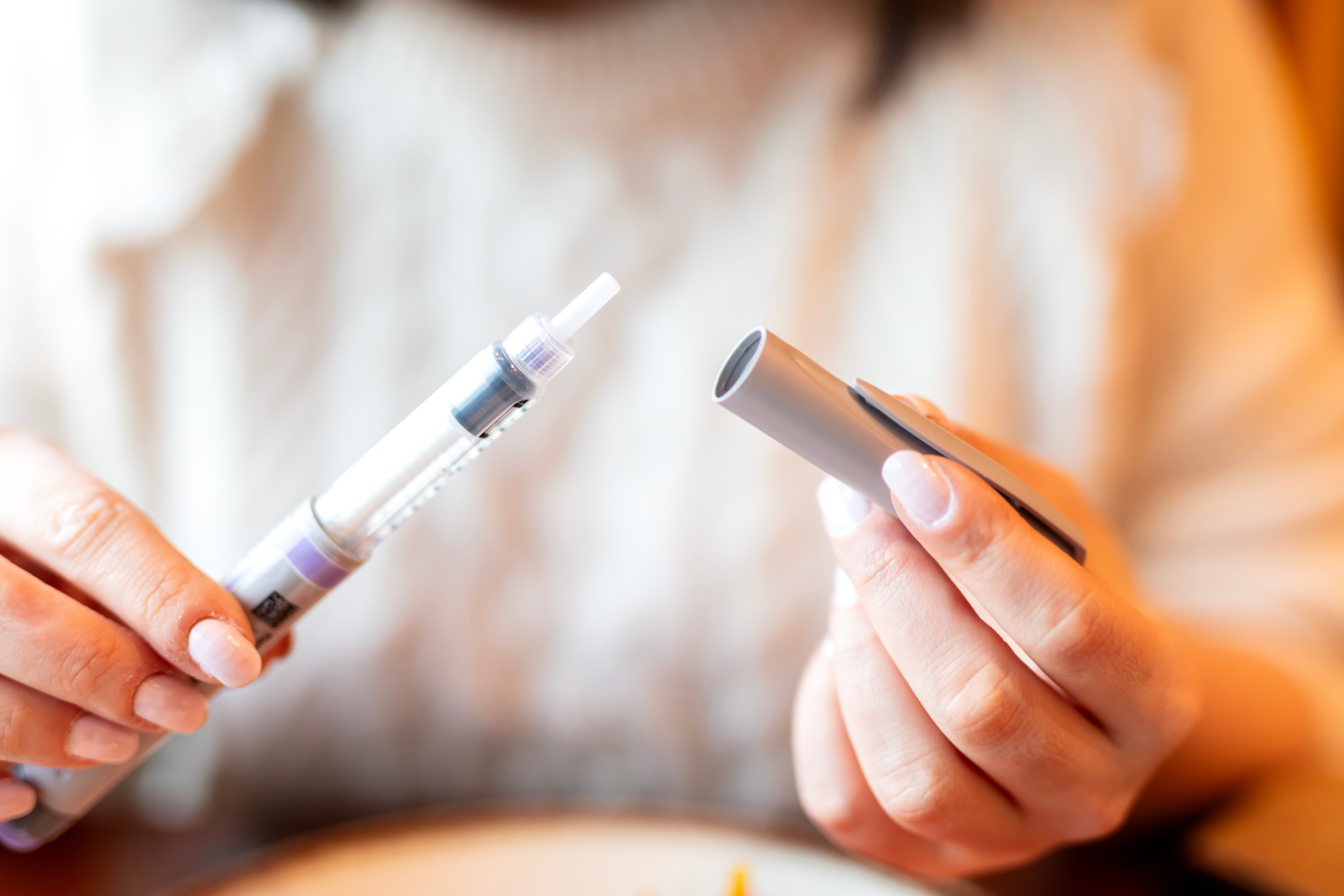 A healthcare professional holding a pen and a pen cap, representing the management of diabetes and obesity medications.